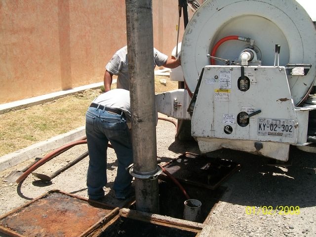 Operador introduciendo manguera de succión en registro