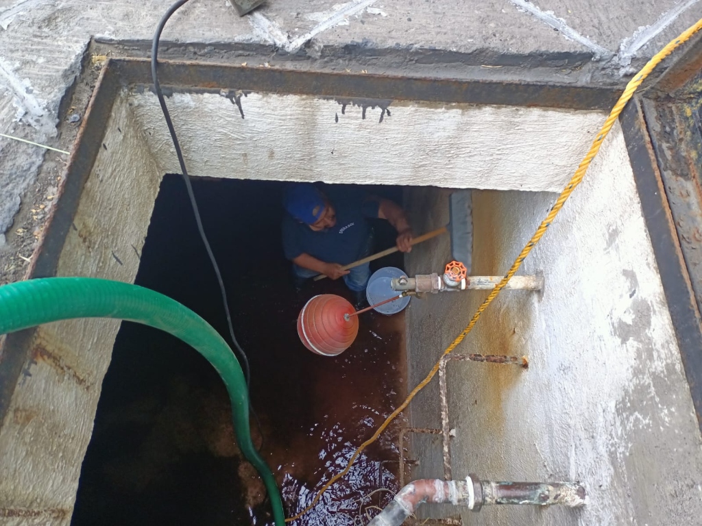 Técnico lavando interior de cisterna subterránea